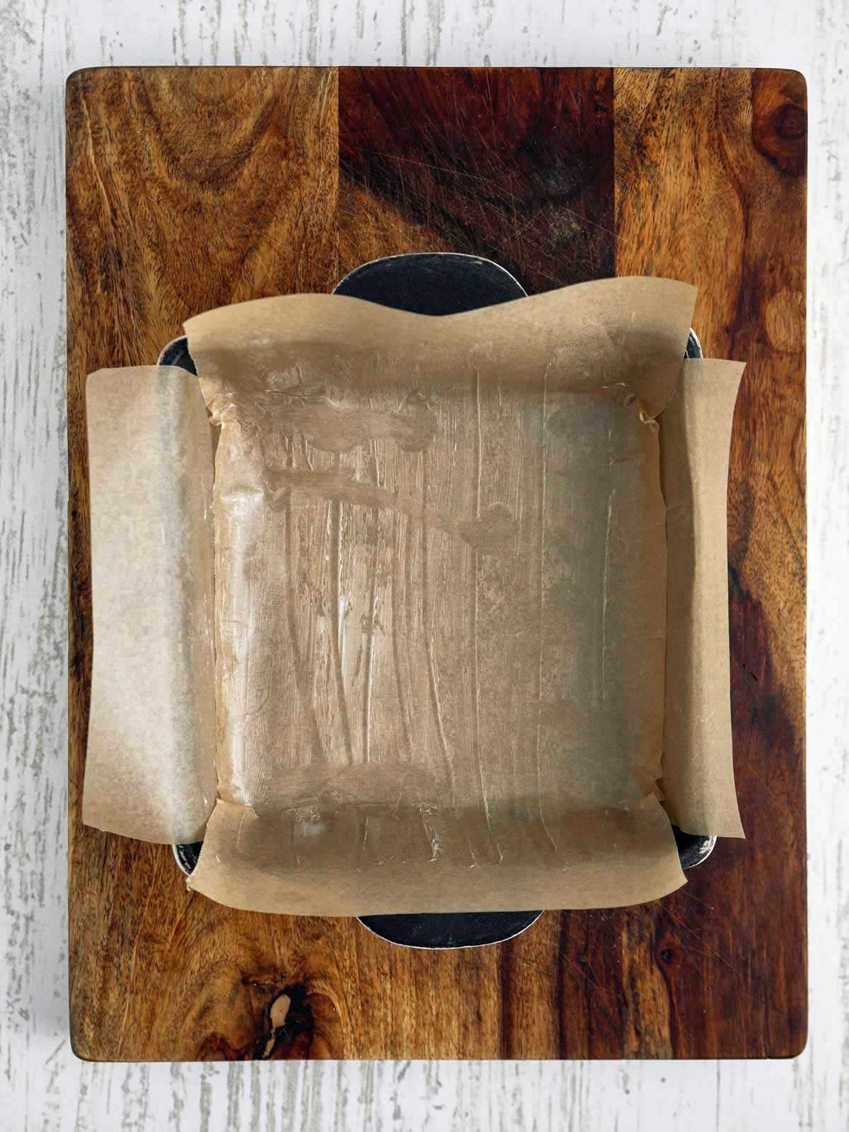Pan with parchment ling extending over the sides.