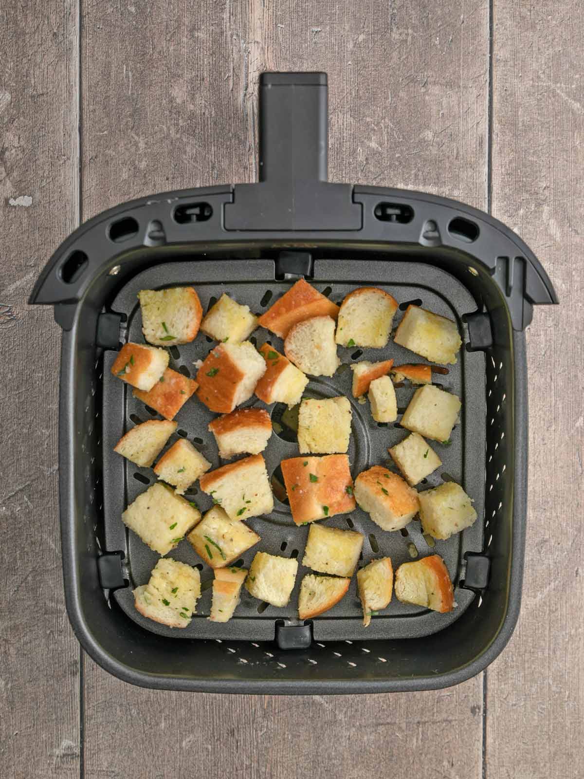 Bread cubes in the basket of the air fryer.