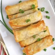 Plate of air fried lumpia with scallion garnish.