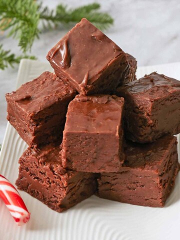 Fully set fudge into squares and stacked on a plate.
