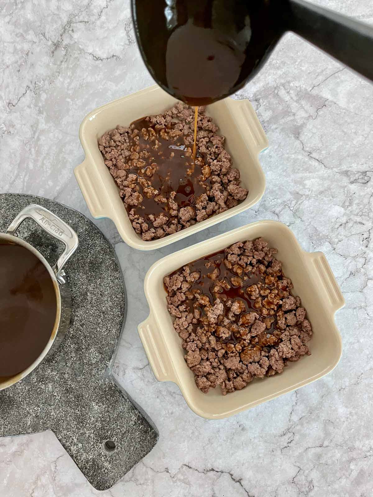 Ladle pouring brown gravy over the ground beef.