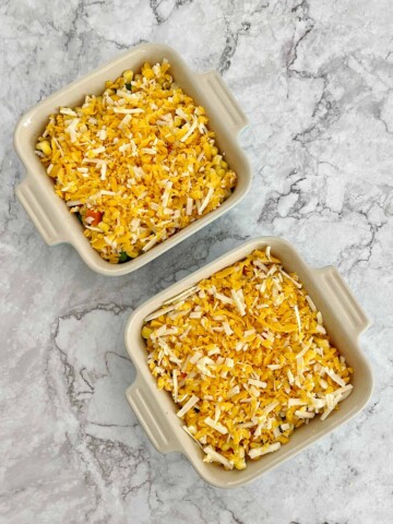Baking dishes with cheese layer placed on top of vegetables.