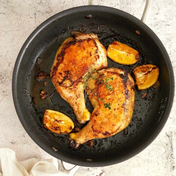 Cooked, golden brown chicken pieces in a cast iron skillet.