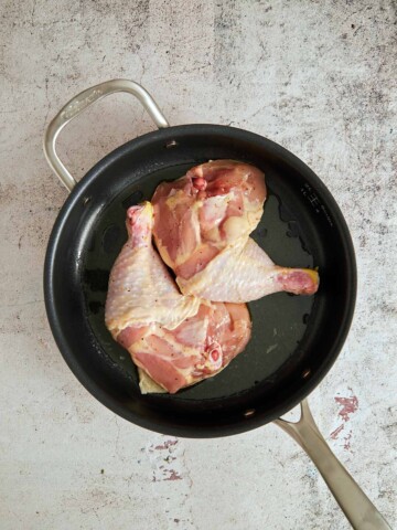 Thigh/drumstick chicken pieces skin side down in the skillet.