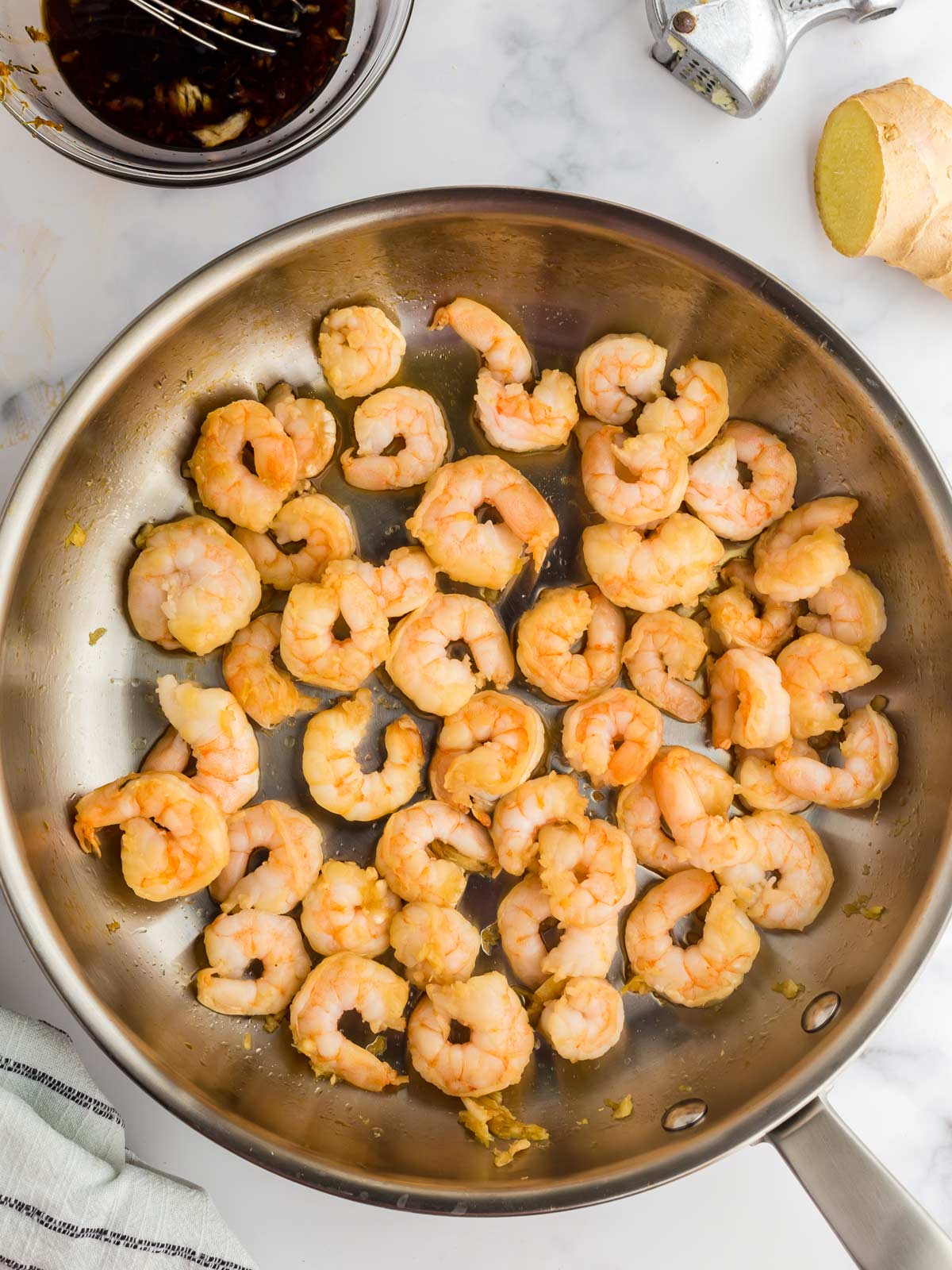 Shrimp in saute pan searing on first side.