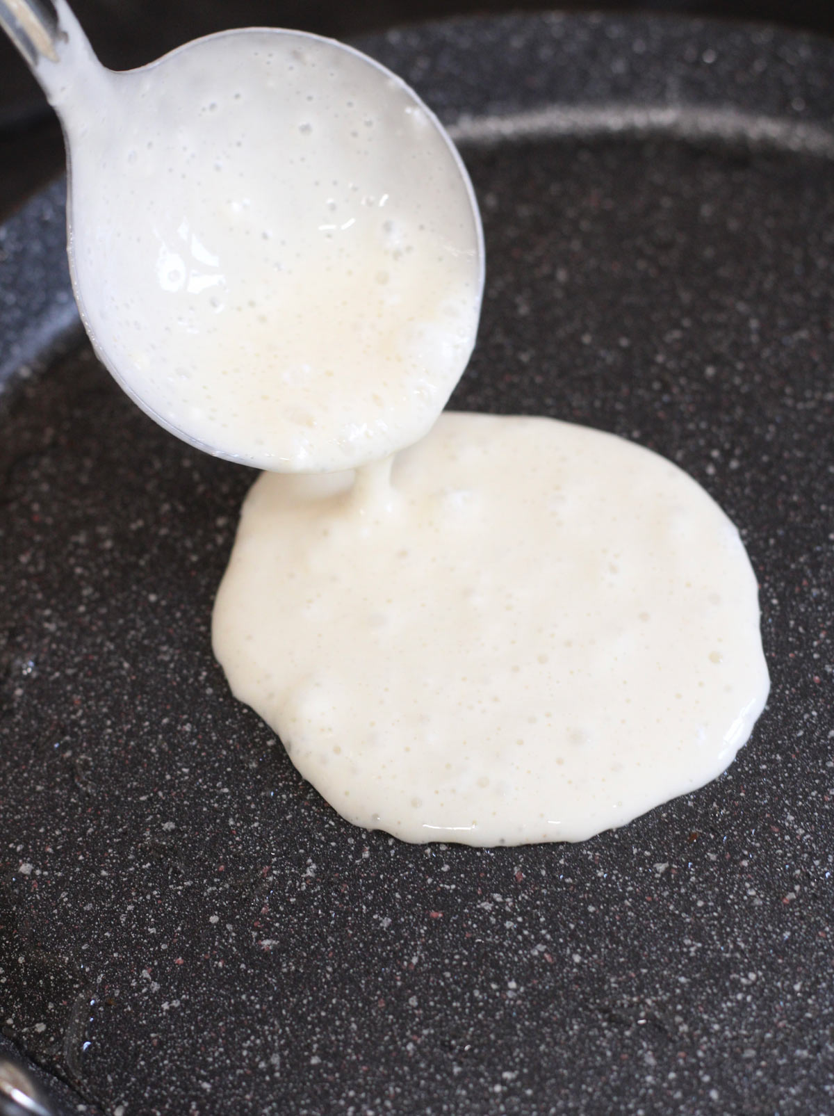 Pouring pancake batter onto a hot griddle.