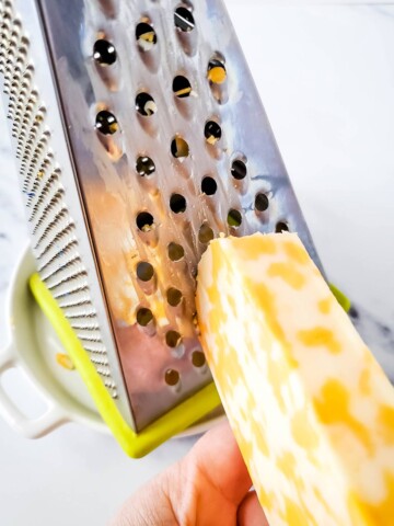 Cheddar/Jack cheese being grated on a box grater.