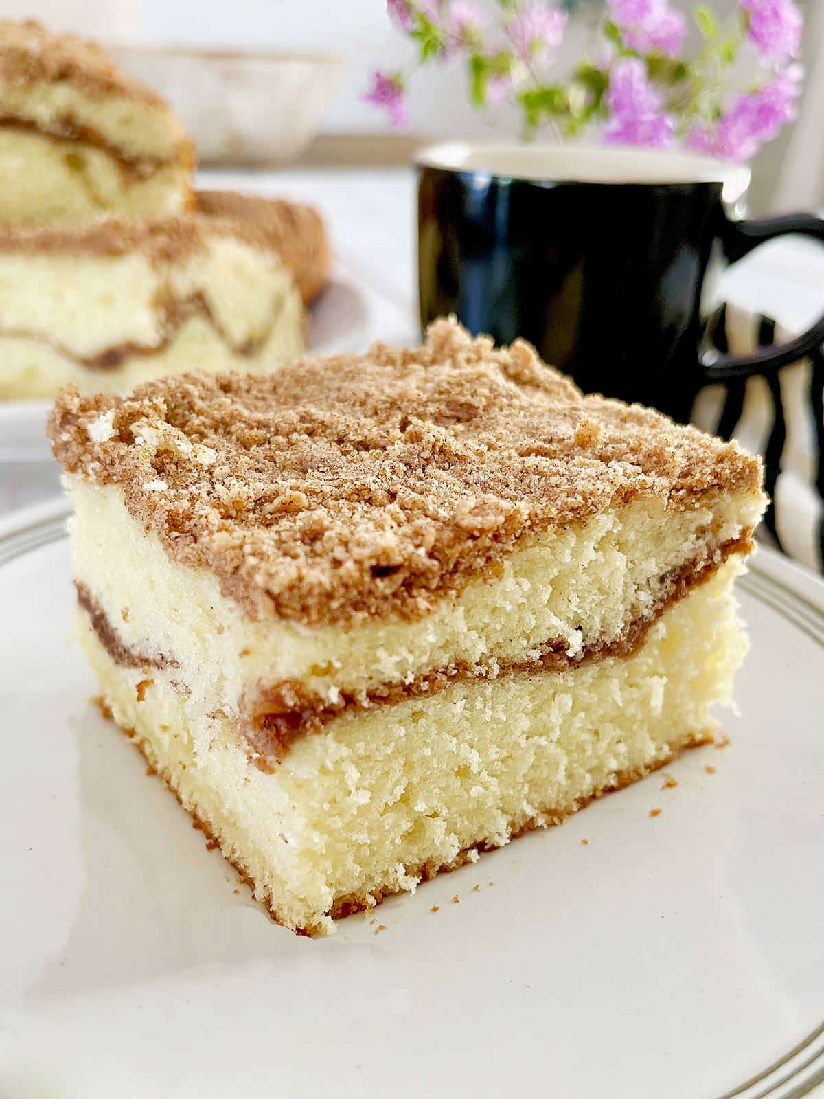 Square slice of coffee cake with cinnamon streusel on top and in the middle.