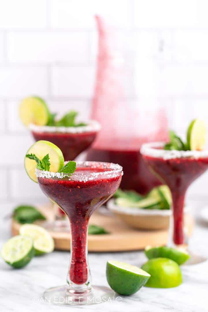 Three cocktail glasses with frozen berry cocktails.