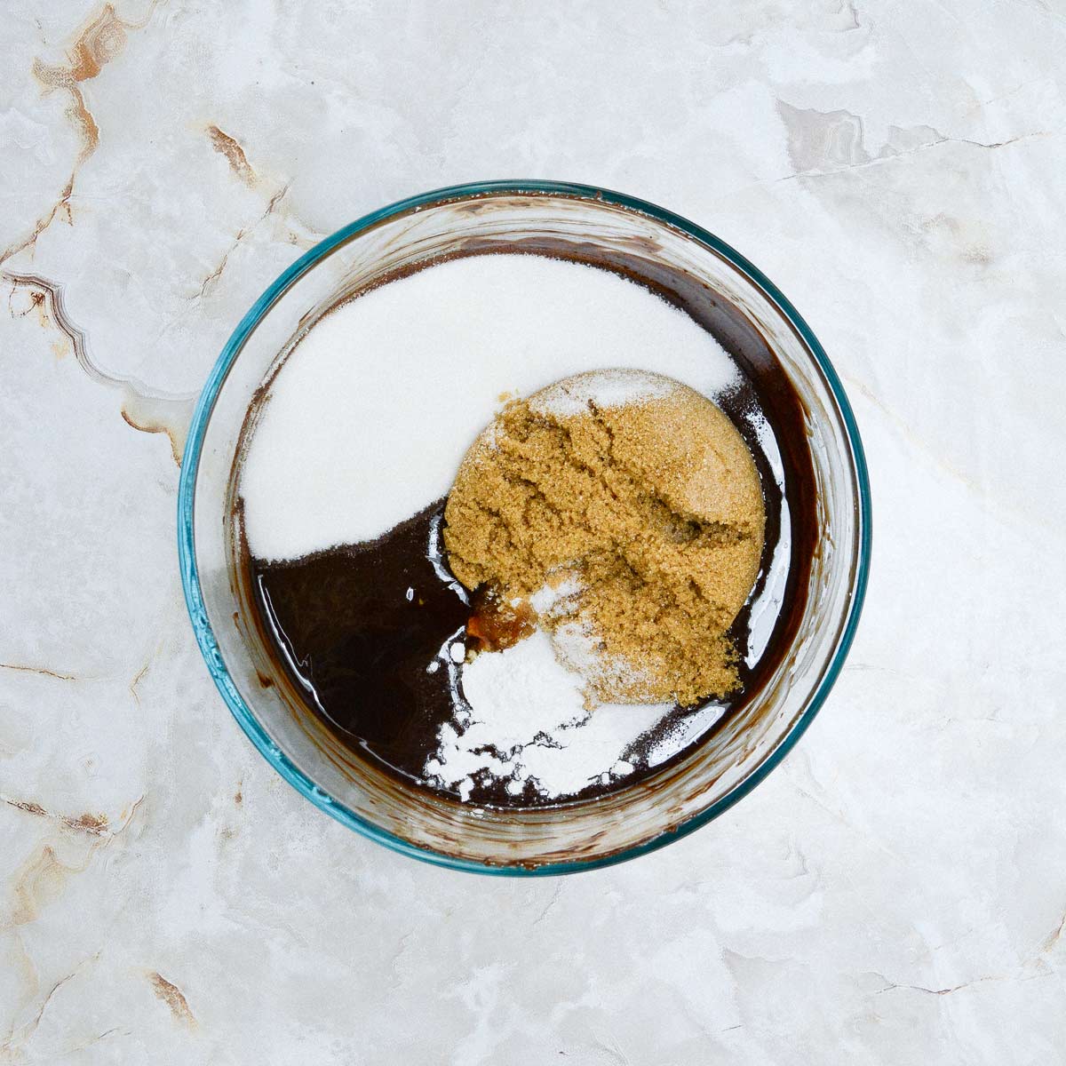 Bowl of meted chocolate with brwon and white sugars added.