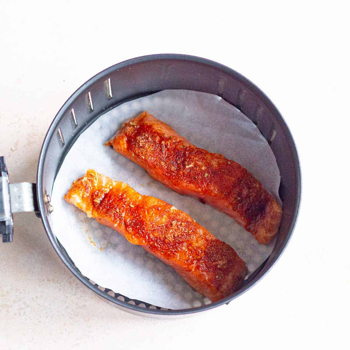 Two salmon fillets in the air fryer basket.