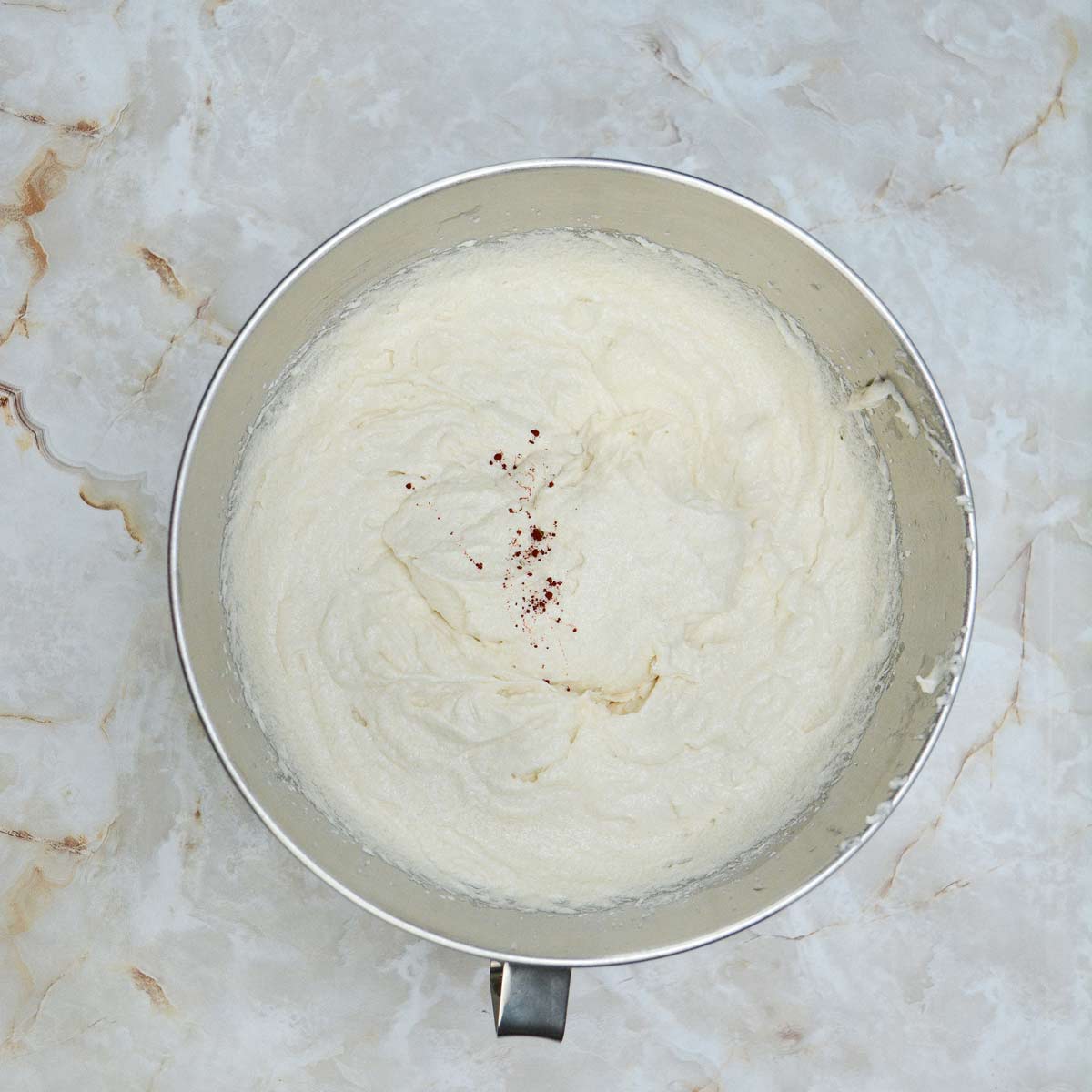 Mixed cake batter with drops of orange food coloring.