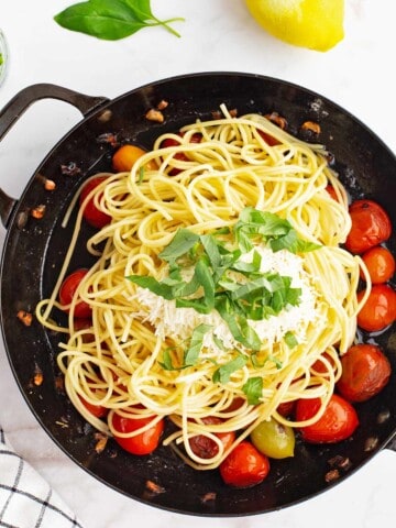 Cooked cherry tomato sauce with pasta, cheese, and basil added.