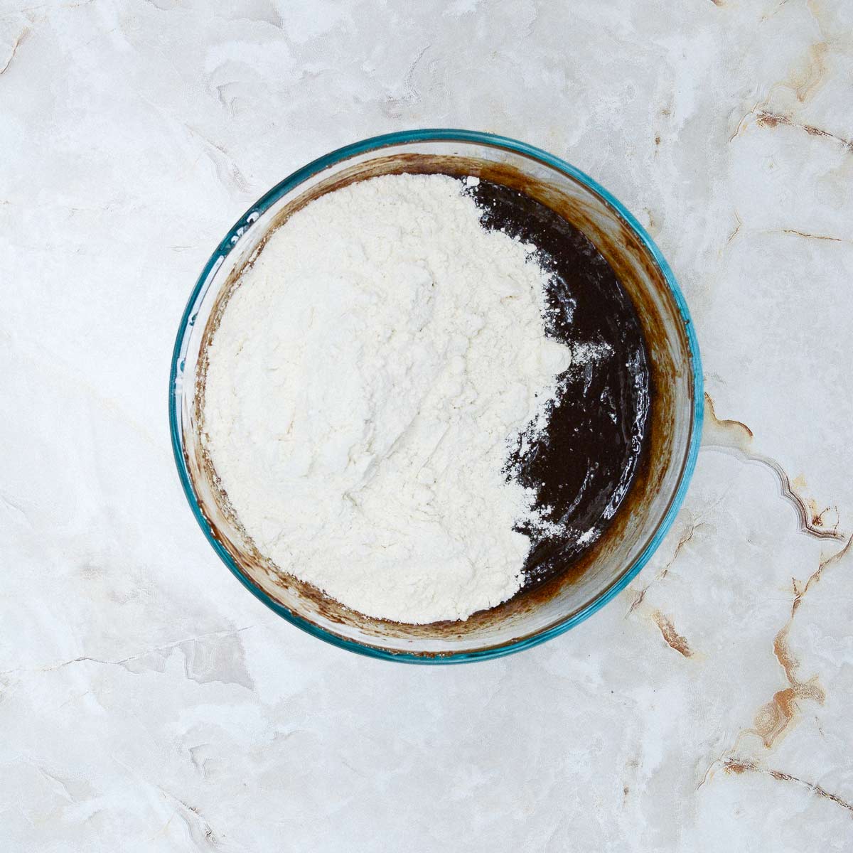 Flour added to the bowl with the brownie batter wet ingredients.