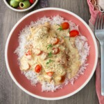 A plate of chicken and rice with sauce.