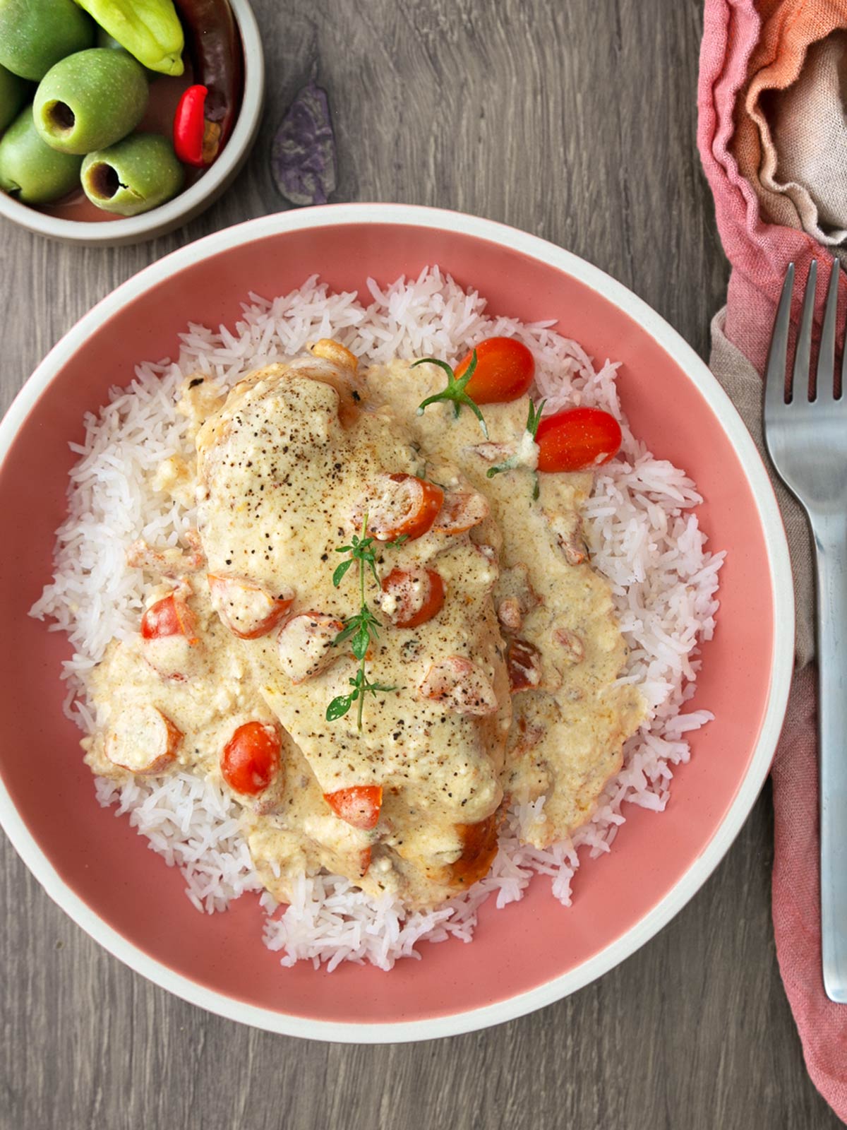 A plate of marry me chicken with rice and tomato garnish.