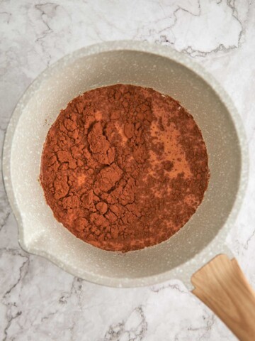 Pot with milk and cocoa powder on top.