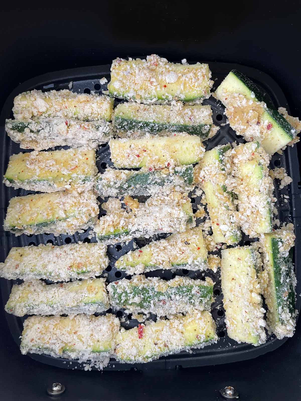 Single layer of breaded zucchini ready to be cooked in the air fryer.