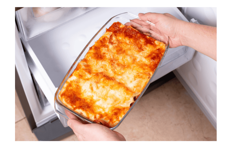 Woman placing lasagna in the freezer.