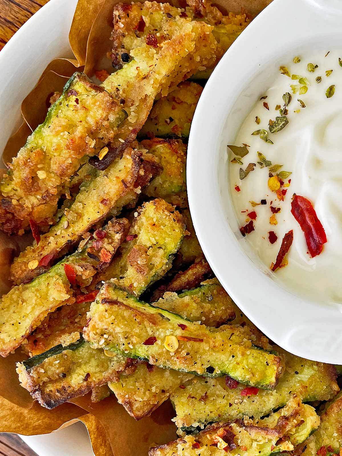 Plate of golden brown zucchini fries with a garlic aioli dipping sauce.