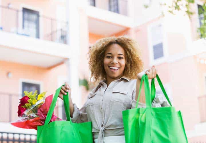 Happy woman holding up twp green shopping bags.