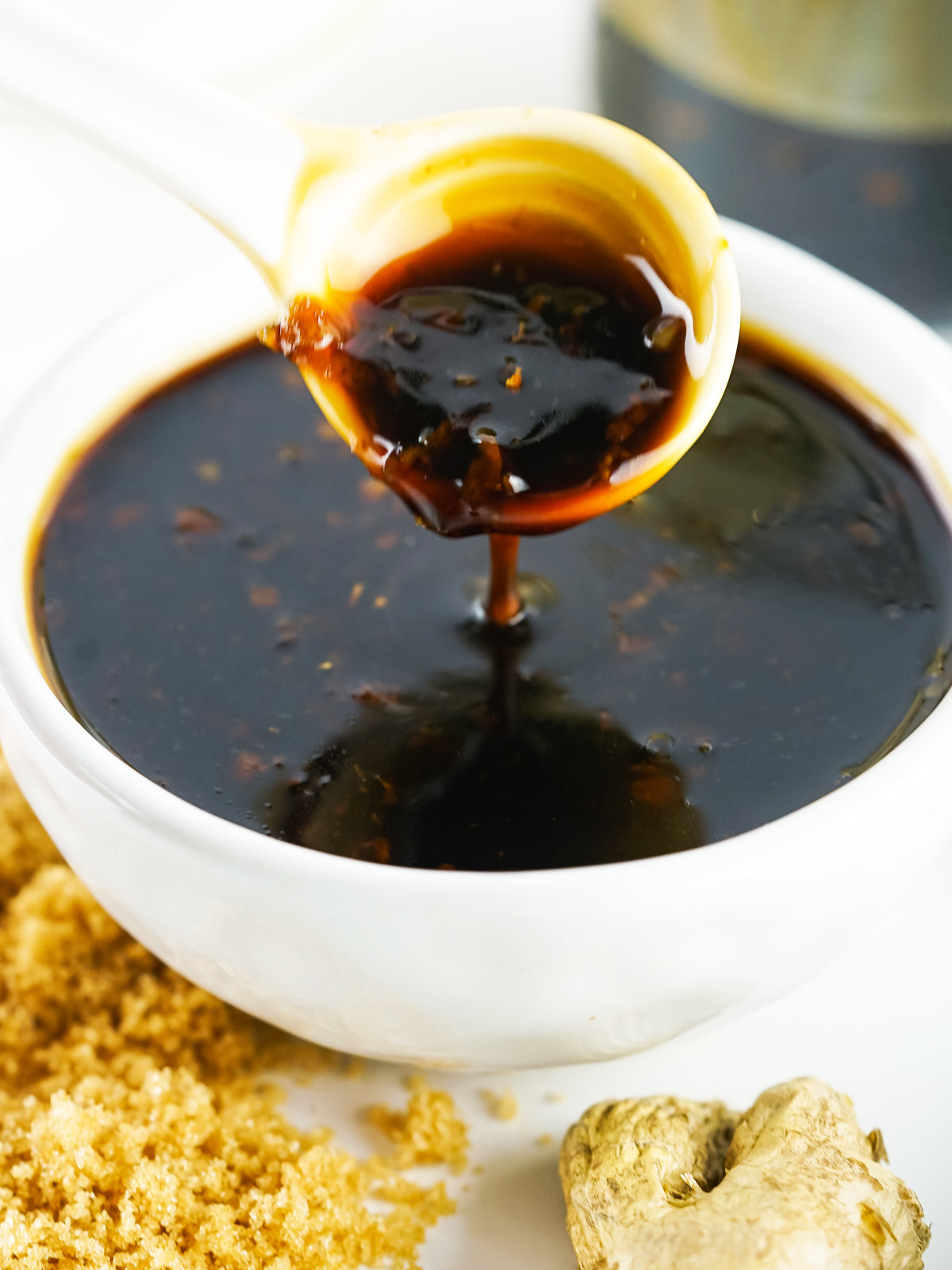 Bowl of thick teriyaki sauce dripping from a small ladle.