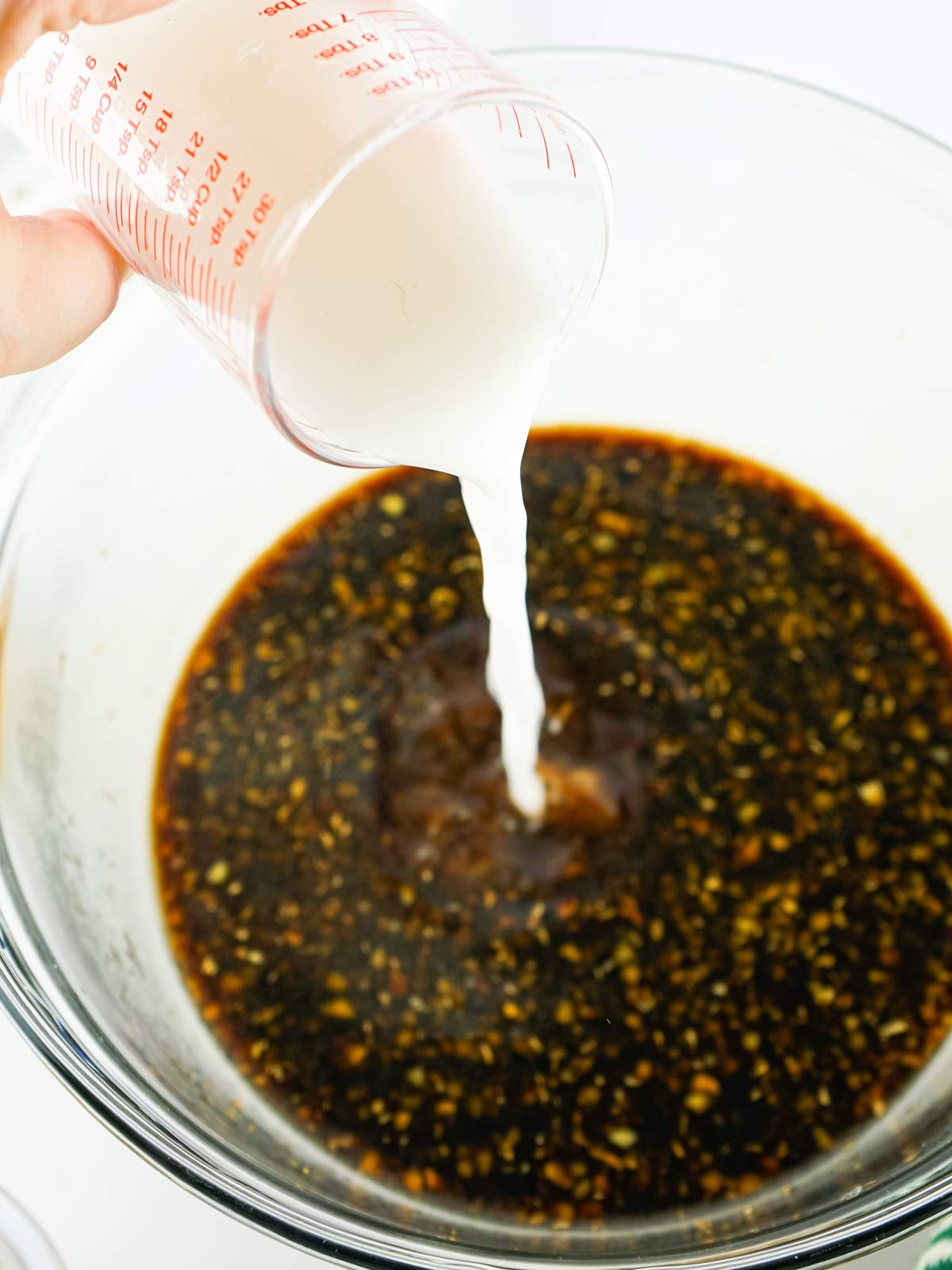 Cornstarch and water slurry being poured into the hot teriyaki sauce.