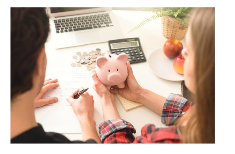 A man and woman putting money into a piggy bank.