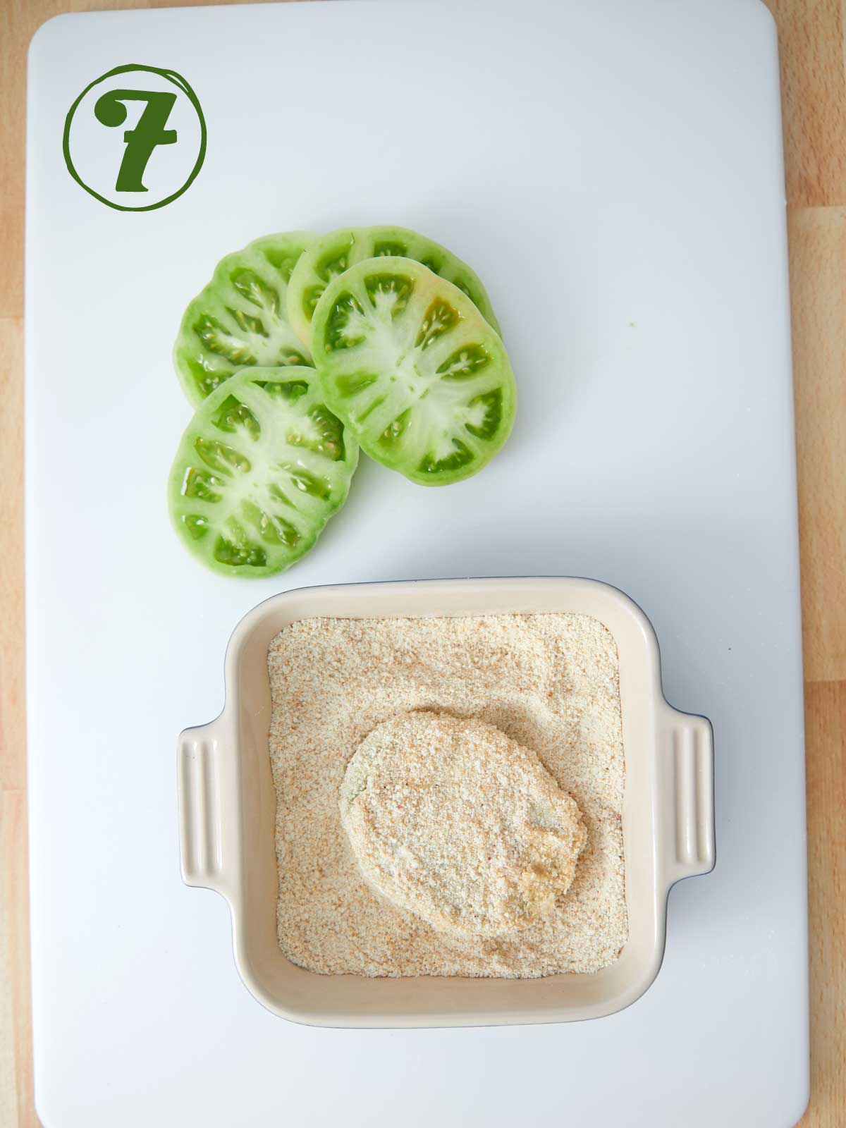 A cutting board with a bowl of tomatoes and a bowl of flour, perfect for preparing a fried green tomatoes recipe.