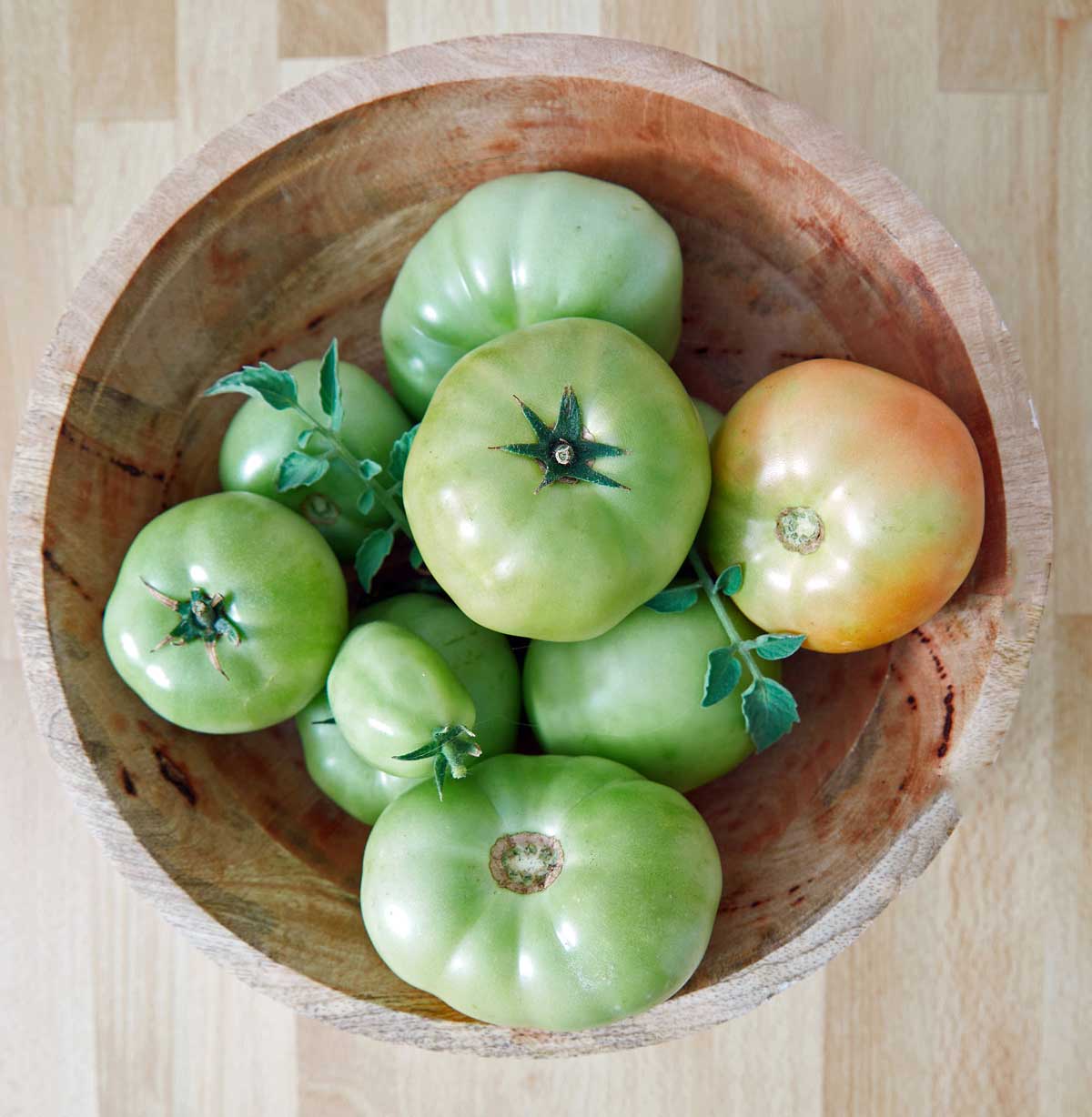 Green tomatoes served in a wooden bowl.
