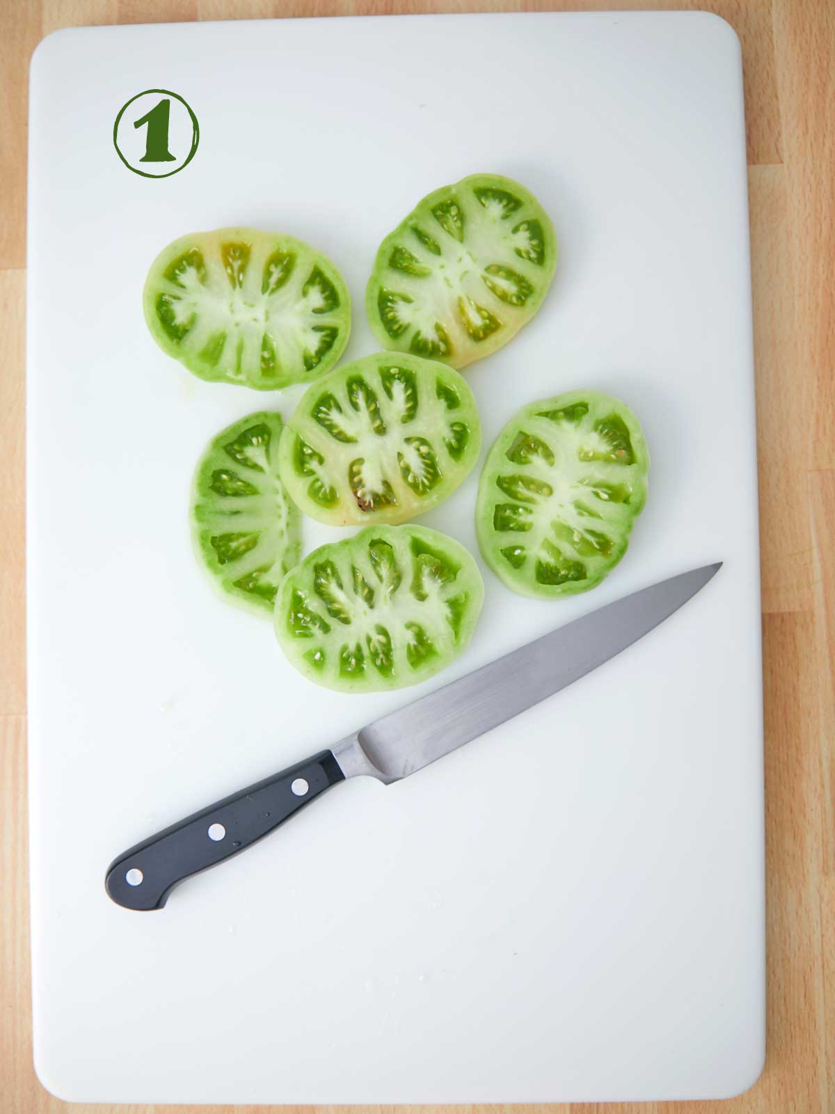 Sliced tomatoes on a cutting board ready for a fried green tomato recipe.