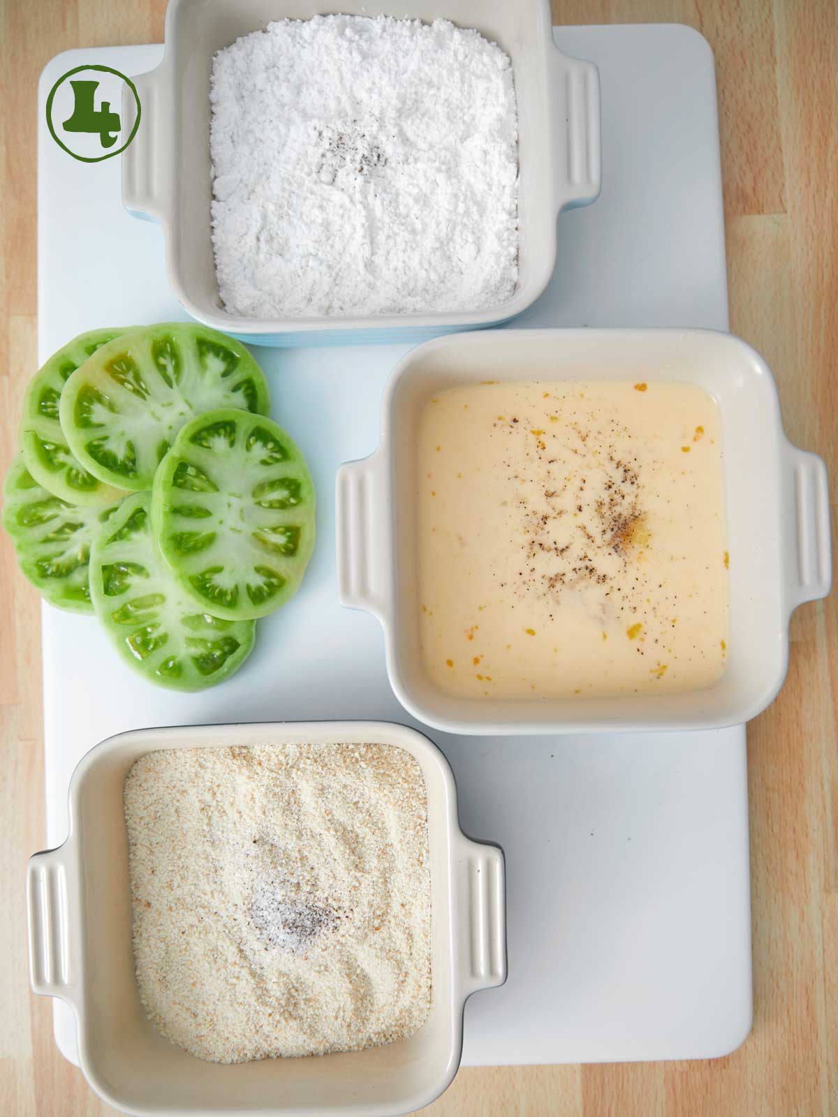 Recipe for fried green tomatoes with four bowls containing flour, salt and tomatoes.