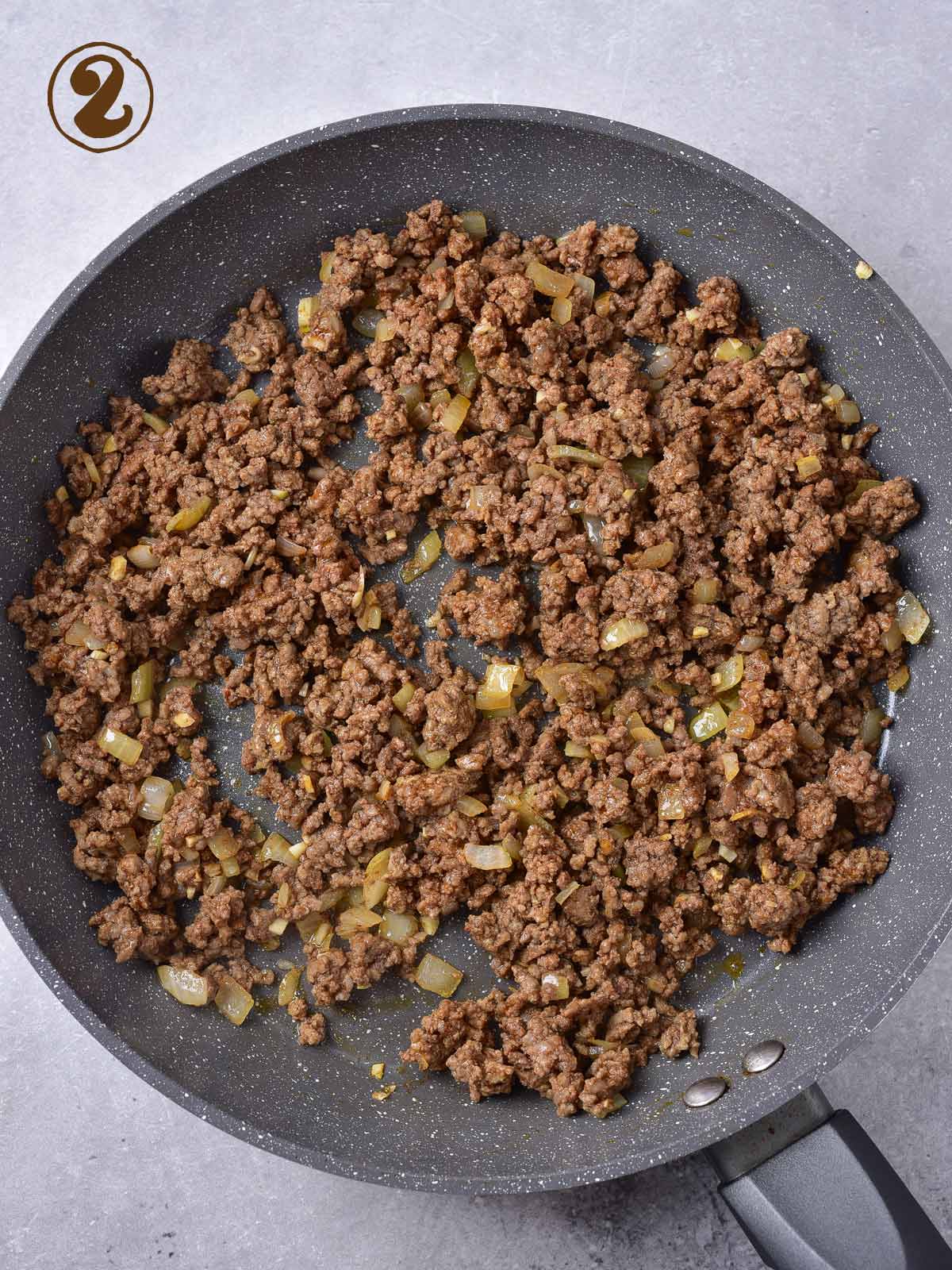 A frying pan with ground beef and onions.