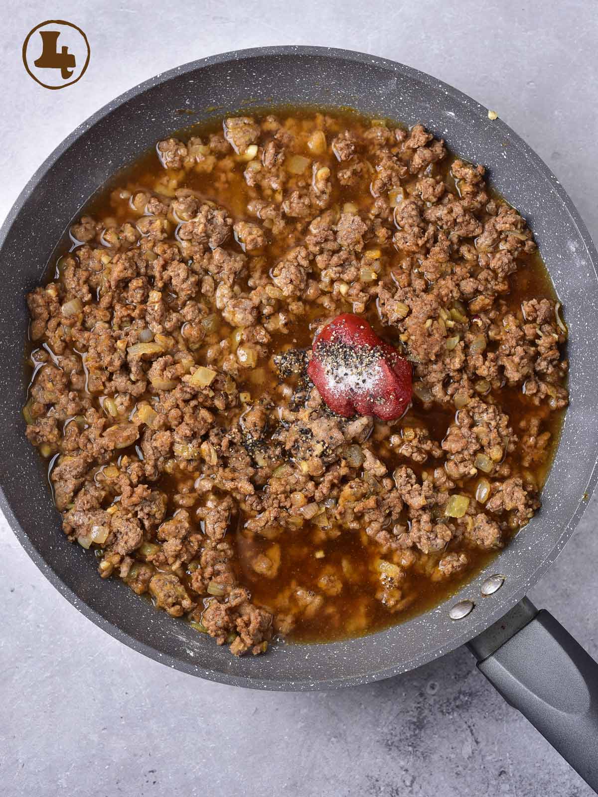 A frying pan with meat and tomato paste in it.