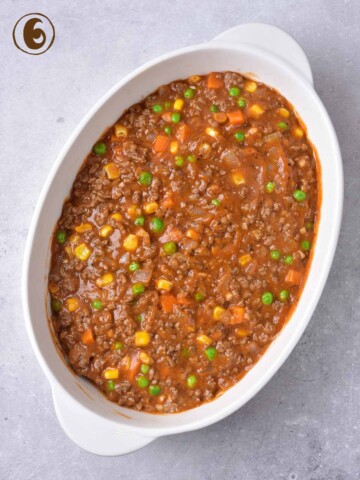 A dish of beef with vegetables and peas.
