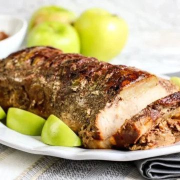 A pork roast with apples and apples on a plate.