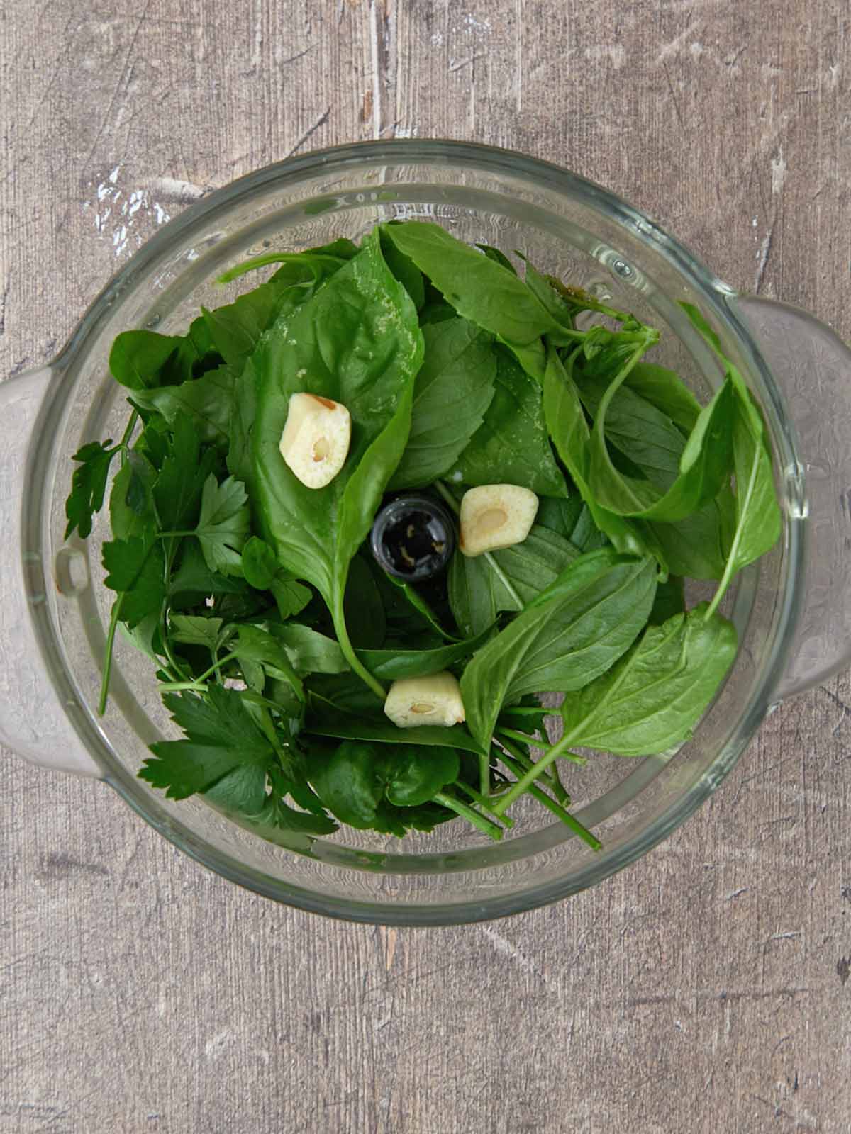 Basil, parsley, and garlic in a mini food processor.