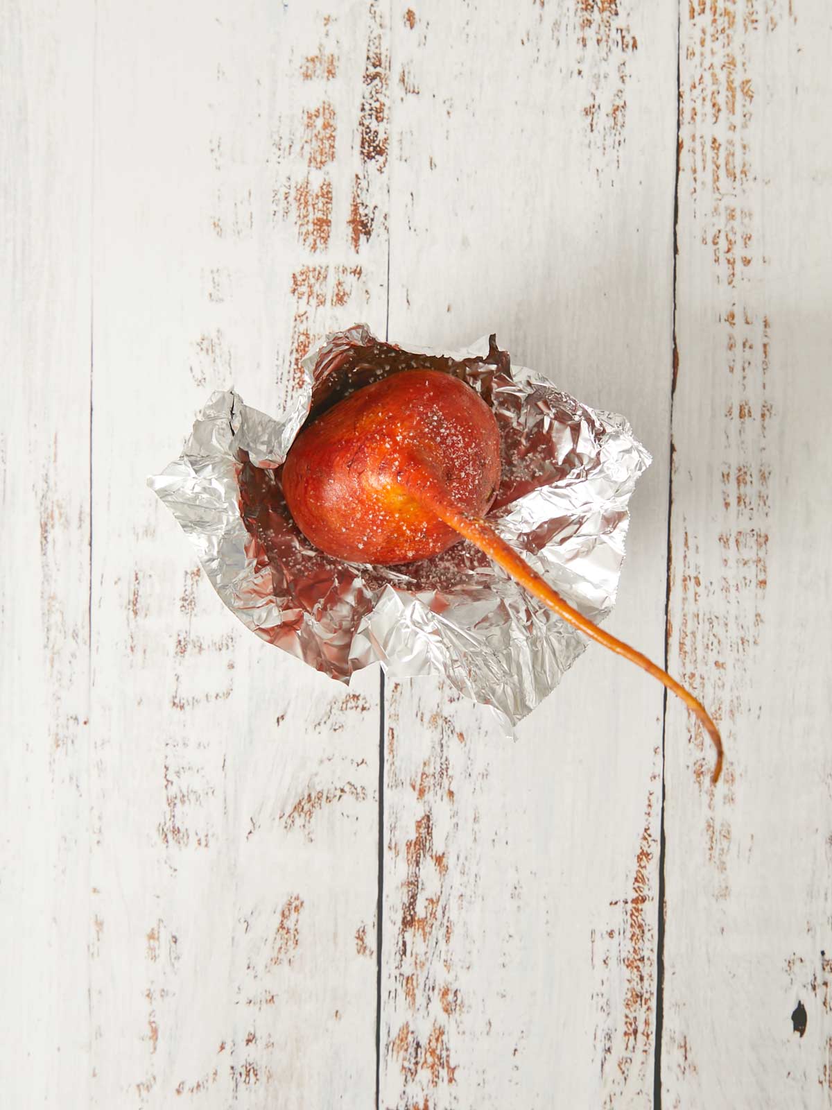 A golden beet on a board and square pies of foil.