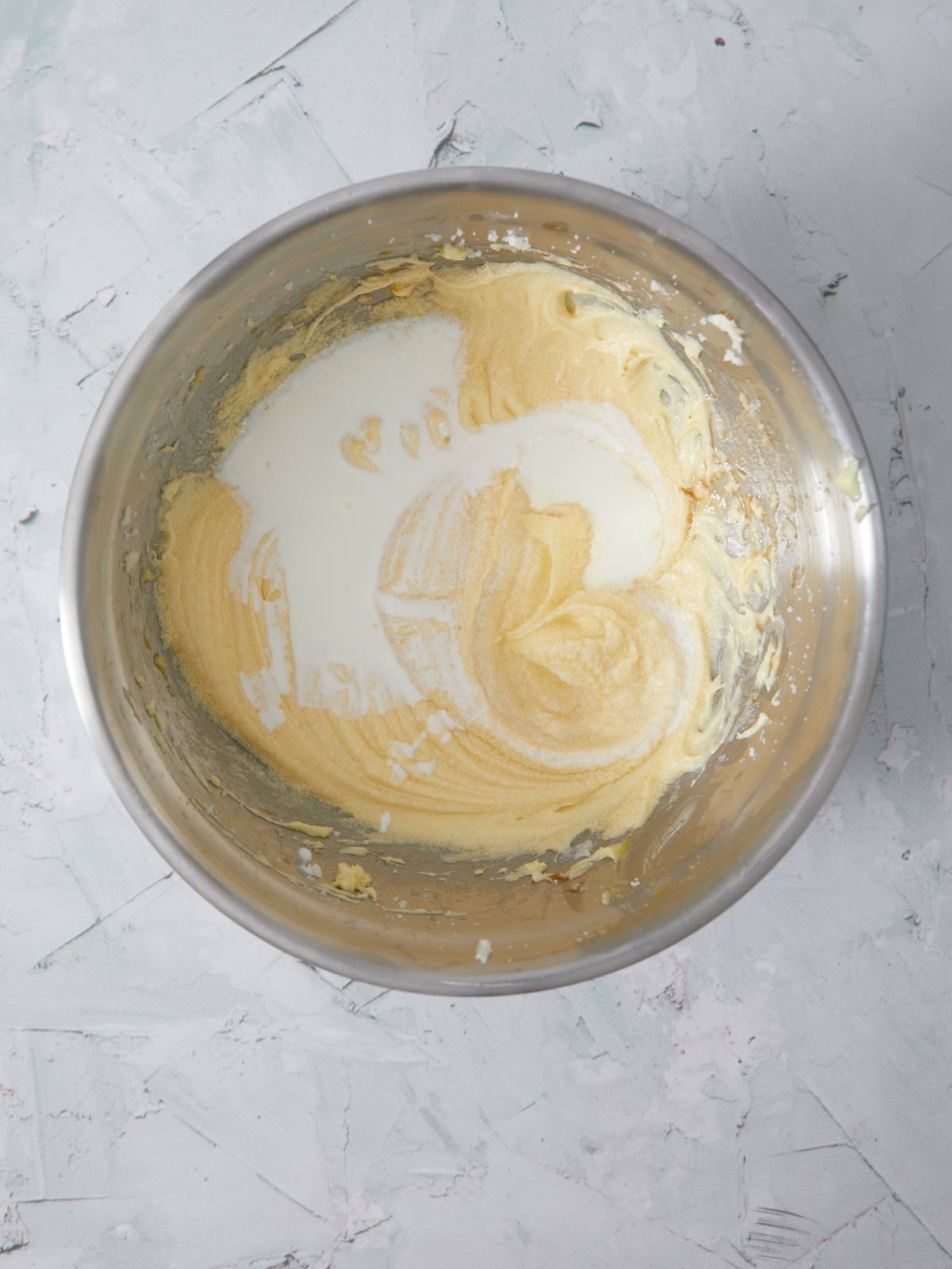 Buttermilk poured into the bowl with the butter and sugar.