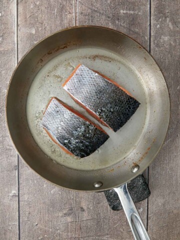 Salmon fillets skin side down in the saute pan.