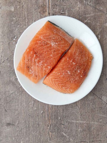 Two salmon fillets with salt and pepper.