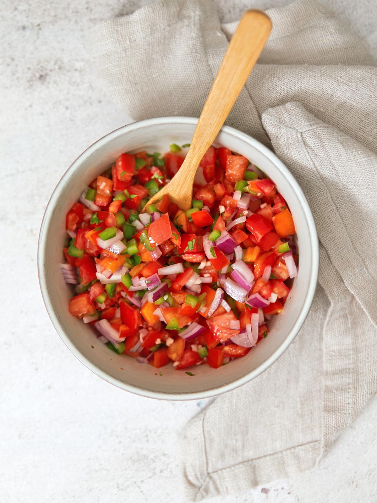 All of the chopped ingredients, salt and lime juice combined in a bowl.