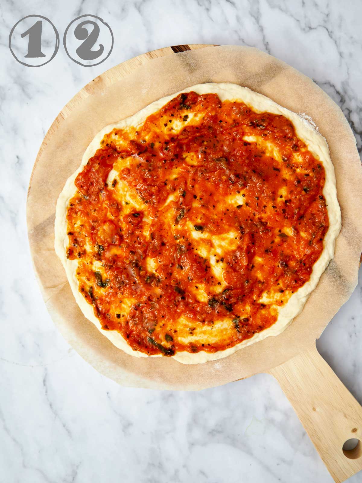 PIzza sauce on a pizza dough round.