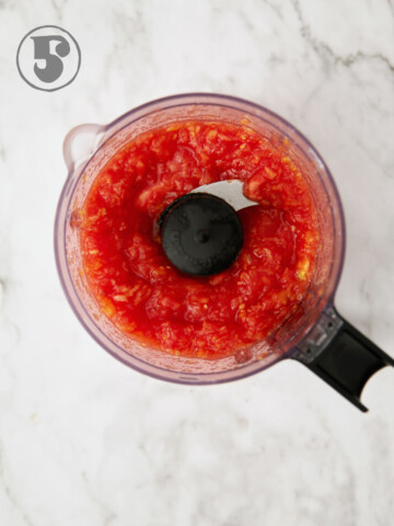 Chopped tomatoes in the bowl of a mini food processor.