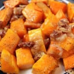 A plate of roasted sweet potatoes with pecans on it.