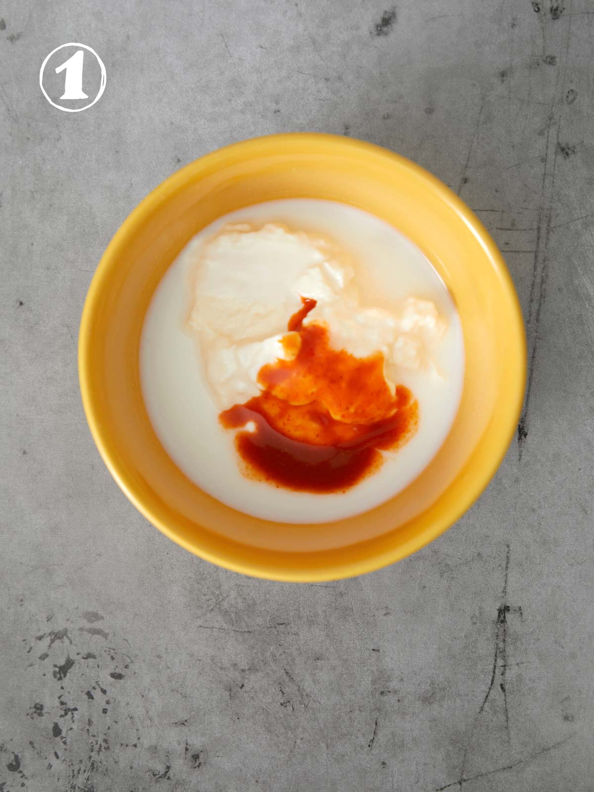 A bowl of mayonnaise and buttermilk with hot sauce in it.