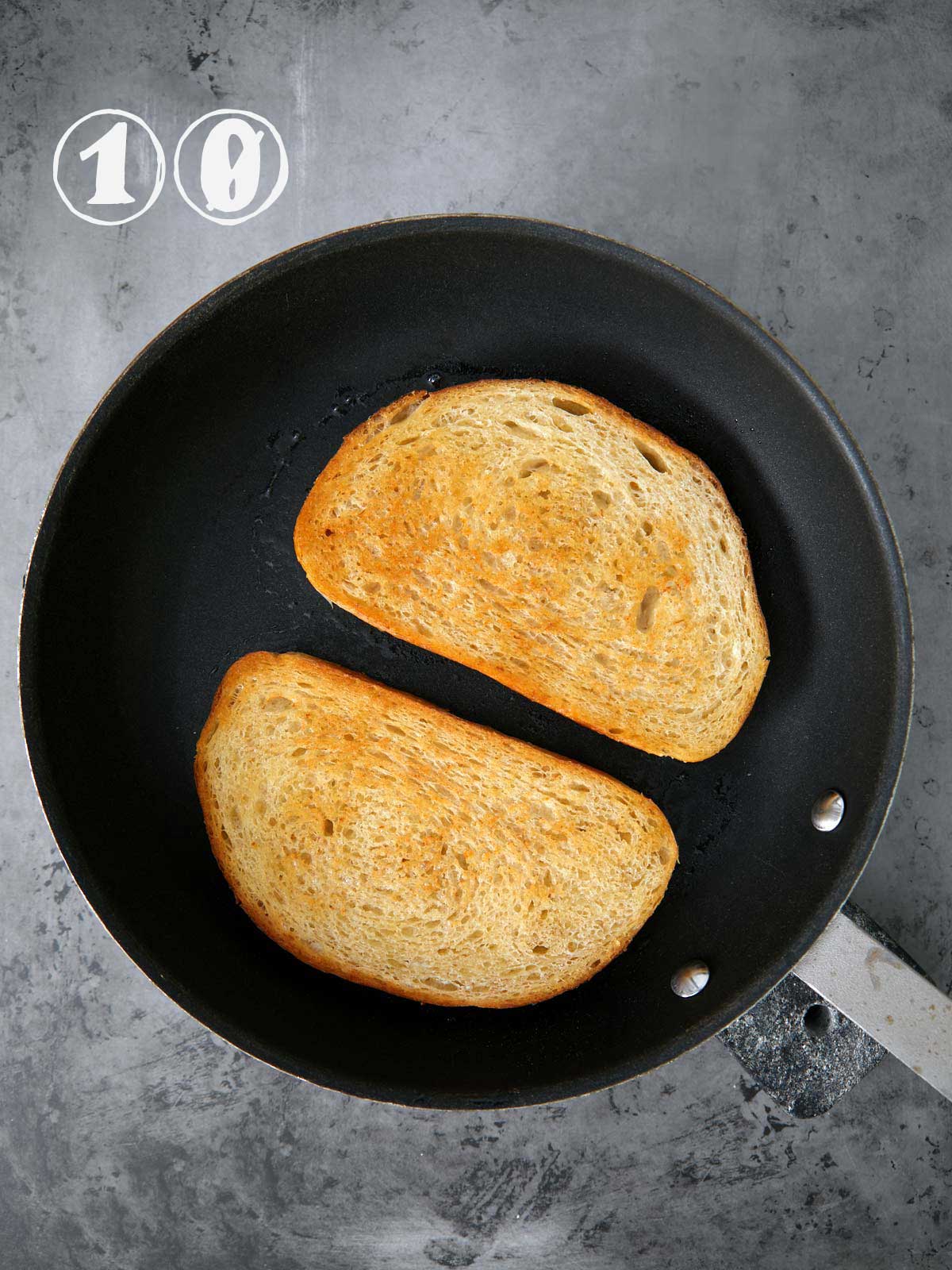 Two slices of bread with fried green tomato in a frying pan.