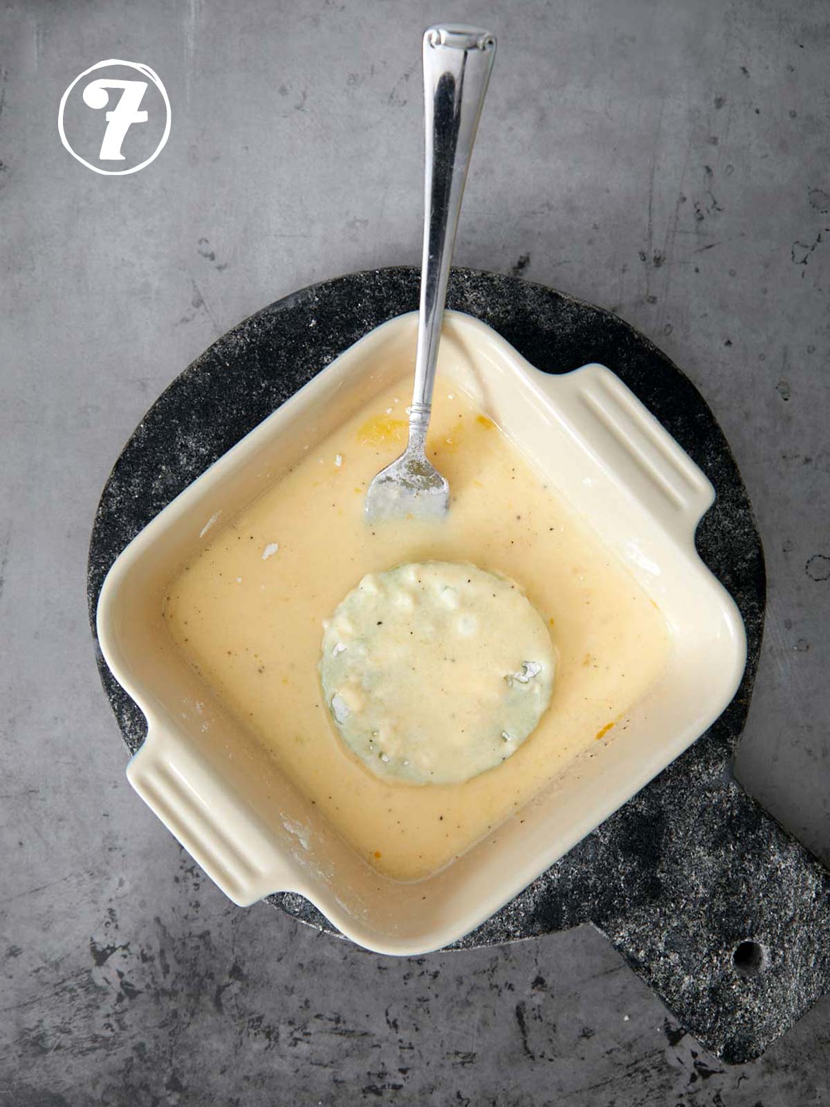 A bowl of egg mixture with a fork in it with a green tomato.