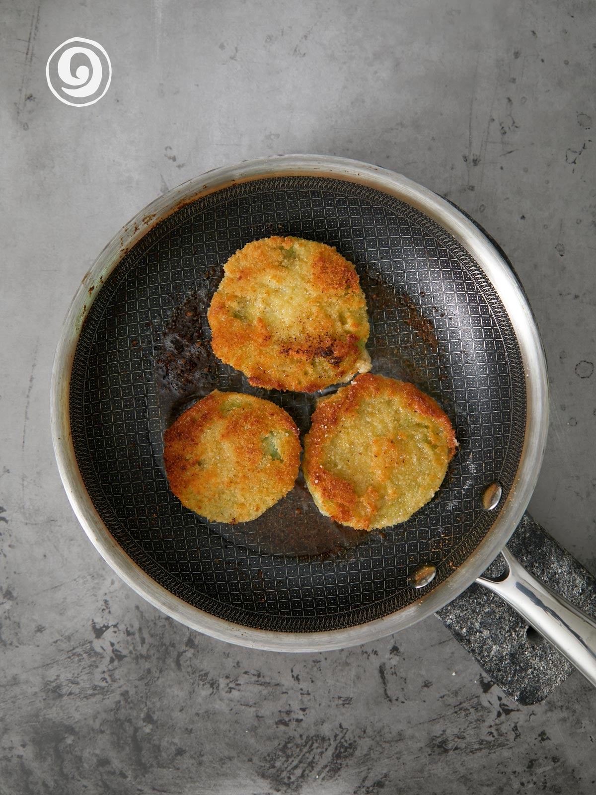 Fried green tomaoes in a frying pan.