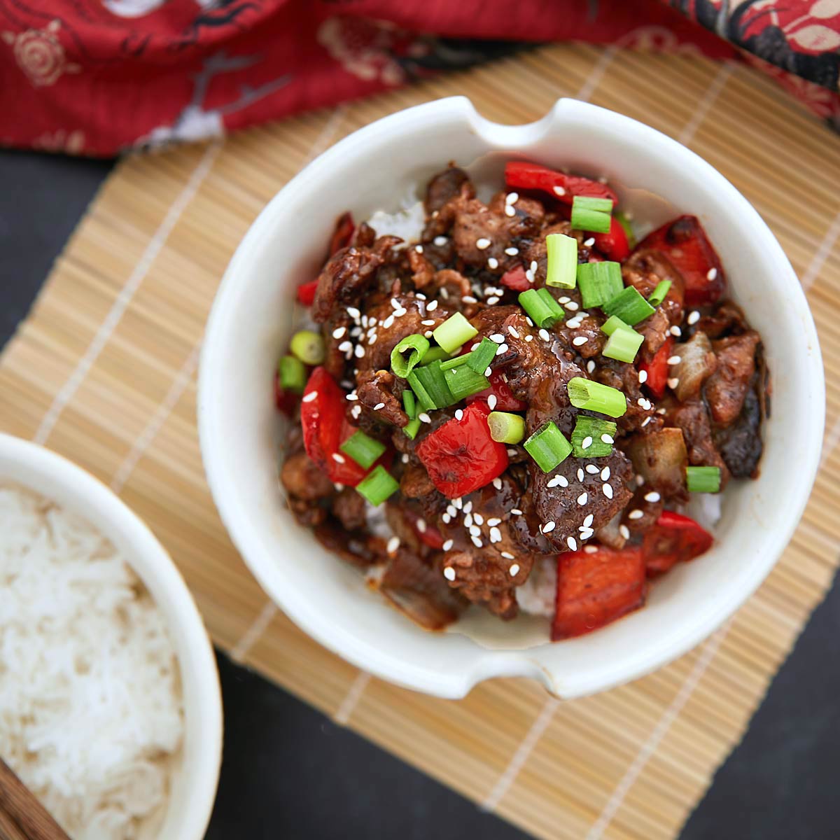 Beijing beef stew in a bowl with rice and sesame seeds.